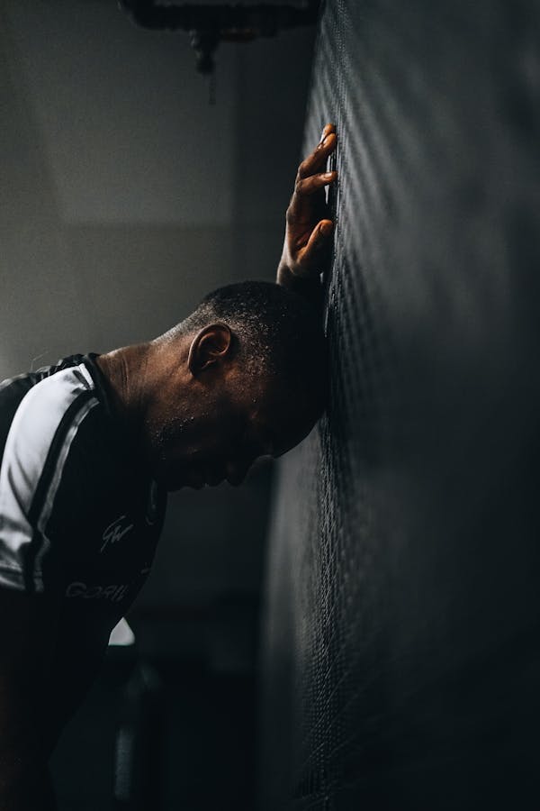 Sportsman leaning against wall in frustration